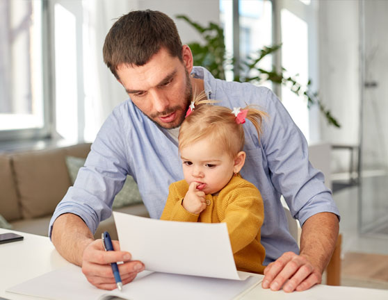 Hombre visualizando un documento mientras sostiene a su hija pequeña