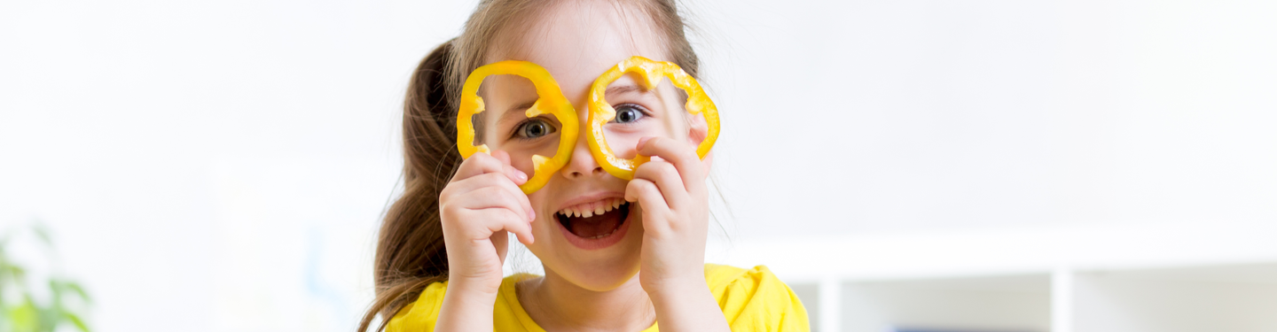 Niña haciendo una gafas con dos rodajas de pimiento amarillo