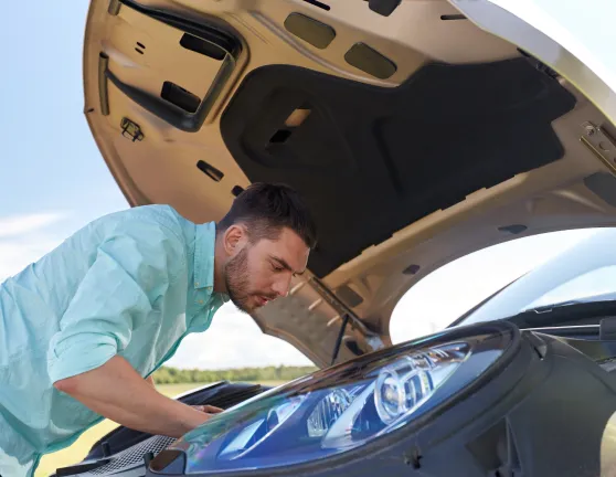Hombre con el capó subido mirando si existe algún problema en el interior del coche