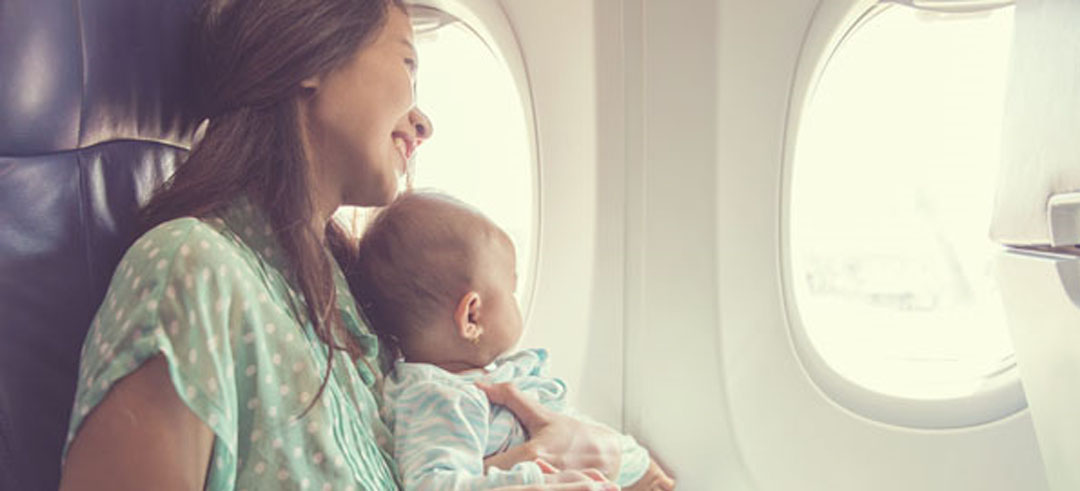 Mujer con un bebe en brazos sentada en un avión